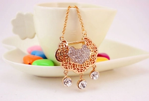 Detail of gold hollow long命锁 pendant with crystals and coin pattern on a white cup