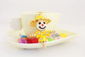 Detail of creative rhinestone scarecrow keychain with yellow enamel in a coffee cup setting