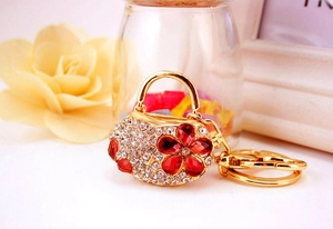 Detail of gold alloy handbag keychain with sparkling rhinestones and red floral gems