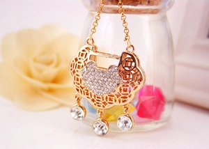 Detail of golden Chinese Ruyi lock pendant with white crystals and hollow coin pattern