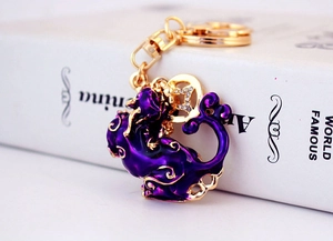Détail du porte-clés animal en émail violet avec cadre doré et strass étincelants
