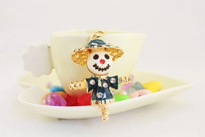 Macro shot of cute scarecrow keychain with blue enamel and rhinestones on a coffee cup