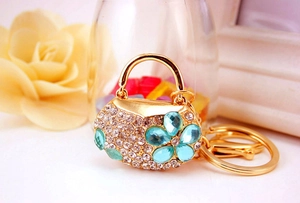 Macro detail of handbag-shaped keychain with gold metal plating and white rhinestones