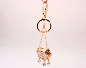 Detail of a golden Chinese lock keychain with sparkling rhinestones and hollow patterns