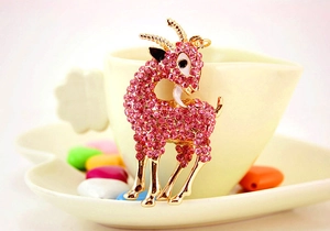 Détail d'un porte-clés chèvre avec strass roses et émail blanc sur une tasse à café