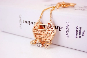 Macro detail of gold Chinese lock keychain with hollow coin patterns and crystal charms