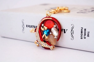 Détail d'un porte-clés lézard en émail rouge avec cristaux et fermoir doré chic