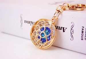 Detailed macro view of golden flower keychain with sparkling blue and white rhinestones