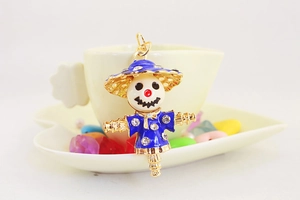 Macro shot of blue enamel scarecrow charm with sparkling rhinestones and gold ring