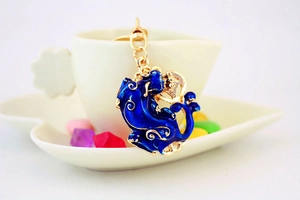 Détail du porte-clés Pixiu en émail bleu avec finition dorée sur une tasse en céramique