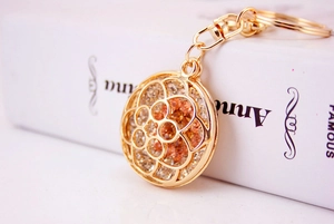 Macro shot of gold-plated hollow flower keychain with inlaid rhinestones on a white book