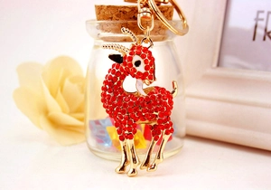 Détail macro d'un porte-clés chèvre plaqué or serti de strass rouges et d'émail blanc élégant