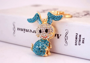 Close-up of golden bunny keychain with sky blue and white rhinestones on white book