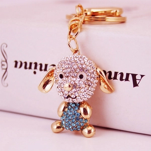 Porte-clés chiot étincelant avec finition dorée et strass bleus sur boîte cadeau blanche