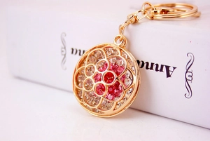 Close-up of sparkling rhinestone flower keychain with gold metal base and lobster clasp