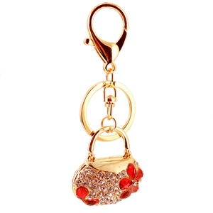 Macro detail of gold purse keychain with white rhinestones and red floral accents