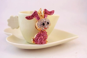 Detail of pink and white rhinestone bunny charm hanging on a cream ceramic cup