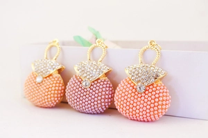 Macro shot of colorful rhinestone handbag charms with pearls in coral, purple, and pink