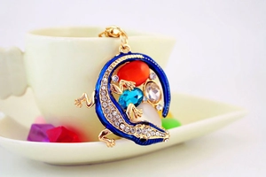 Détail d'un porte-clés lézard en émail bleu avec strass colorés sur une tasse en porcelaine