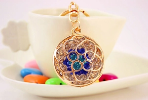 Detailed close-up of hollow flower keychain with vibrant blue rhinestones and gold plating