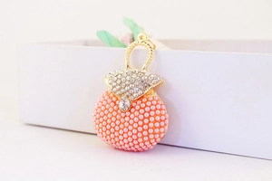 Detailed close-up of a golden mini handbag charm with crystals and coral pink pearls