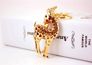 Détail du porte-clés girafe dorée avec motifs de cœurs évidés et finition polie