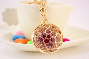Detail of flower keychain with purple rhinestones on a gold metal hollow petal pendant