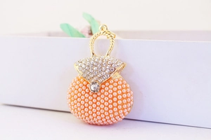 Detail of a handbag-shaped pendant with orange pearls, small crystals and golden handle