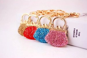 Close-up of four rhinestone handbag keychains in gold, red, blue, and pink on a book