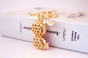 Detailed side view of golden rabbit keychain with pink rhinestones and hollow floral patterns