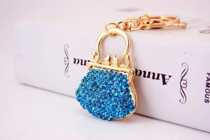 Detail of blue rhinestone studded purse keychain with gold metal frame and handle