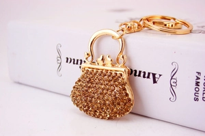 Close-up of golden handbag keychain with amber rhinestones on book background