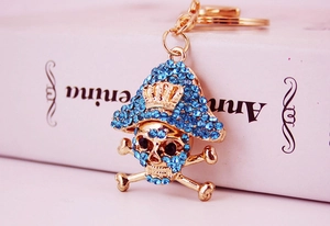 Dettaglio del portachiavi a teschio pirata dorato con strass blu e corona