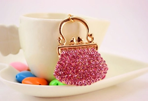 Close-up of a pink rhinestone handbag keychain hanging on a white ceramic cup