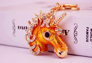 Close-up of golden unicorn keychain with orange enamel and sparkling white rhinestones