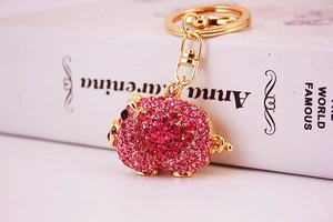 Macro shot of pink rhinestone encrusted pig keychain with red heart pattern and golden hook