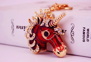 Close-up of golden unicorn keychain with red enamel and sparkling white rhinestones