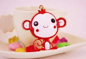 Detail of red cartoon monkey keychain with enamel oil finish and gold-tone metal edges