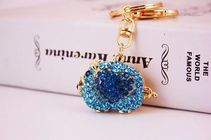 Macro shot of pig keychain with blue rhinestones on a white book surface