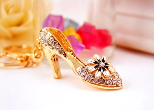 Macro shot of gold high heel keychain with white rhinestones and a daisy flower detail