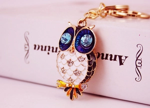 Macro view of crystal owl keychain featuring blue eyes and white enamel details