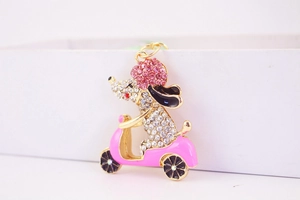 Detalle de llavero metálico de perro con diamantes de imitación rosa en moto