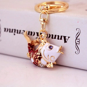 Exquisite koi fish keychain with red enamel and crystals on a decorative book