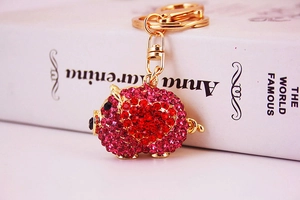 Detail of pig keychain with sparkling red heart rhinestones and golden hardware