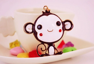 Close-up of cute cartoon monkey keychain with enamel drip finish and golden metal accents