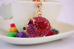 Close-up of golden pig keychain featuring heart pattern with red and pink rhinestones