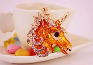 Close-up of golden unicorn keychain with yellow enamel and sparkling rhinestones
