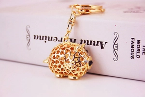 Detail of golden hollow-out pig keychain with heart patterns and metallic finish