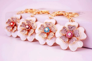 Detailed view of four colorful floral keychains with rhinestones and enamel petals