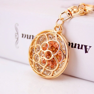 Golden hollow flower keychain pendant with sparkling white and amber rhinestones